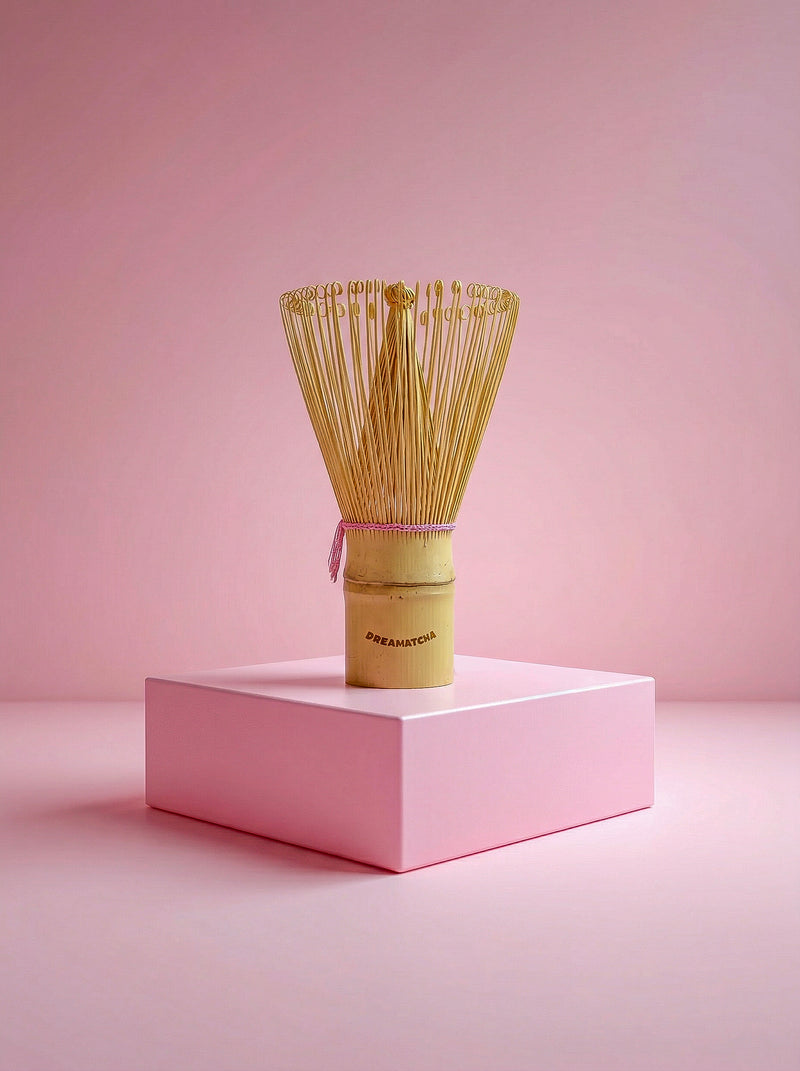 Traditional Japanese tea whisk on a pink platform with a pink background