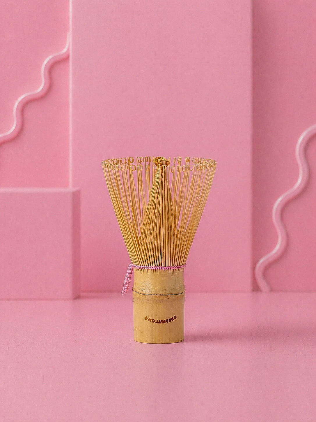Traditional Japanese matcha whisk on a pink background with dreamatcha logo