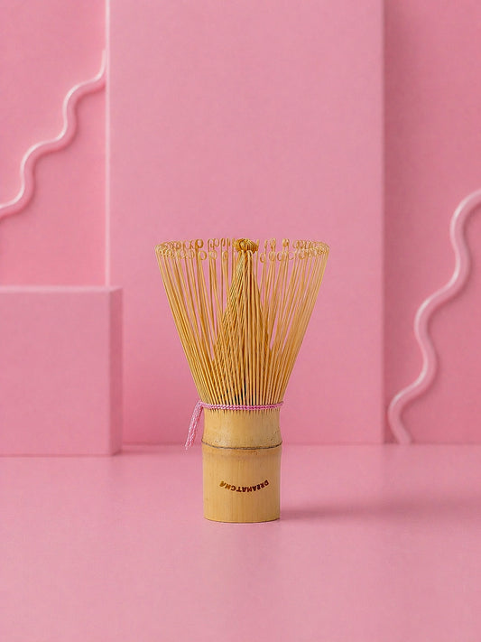 Traditional Japanese matcha whisk on a pink background with dreamatcha logo