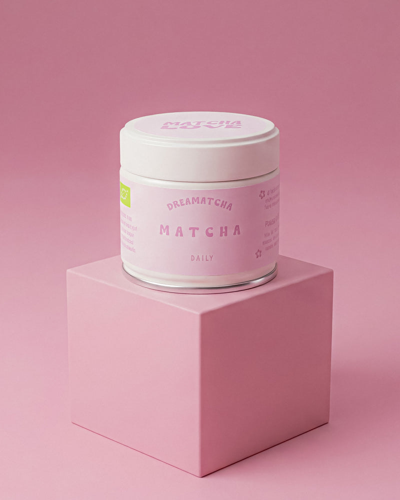 Jar of matcha powder by dreamatcha on a pink platform with a pink background